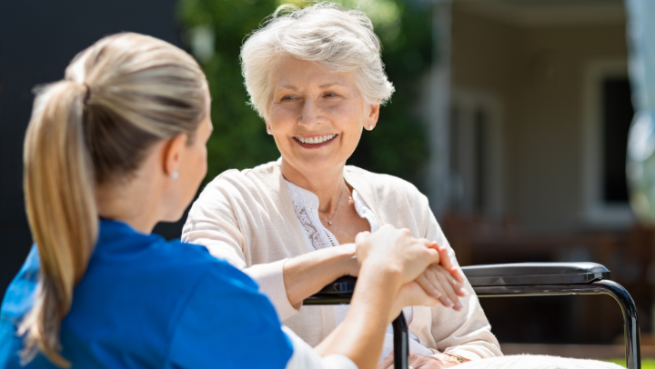a senior lady and her caregiver holding hands