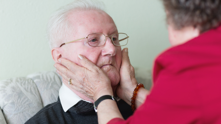 a senior lady holding the face of her elderly husband